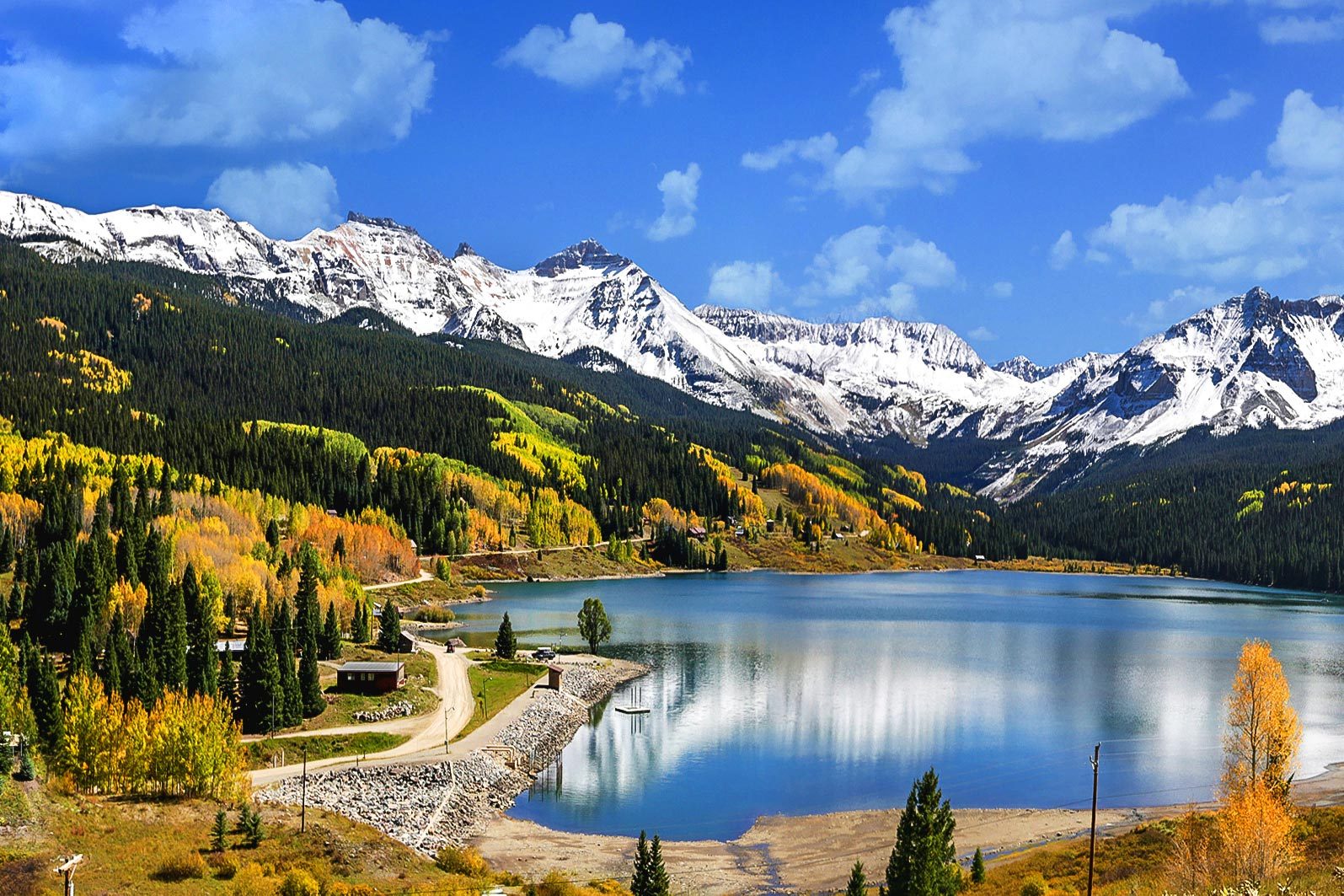 Autumn view of Trout Lake in Colorado. Snowy mountains, aspen and evergreen spruce reflected in the lake.