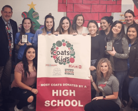 Principal Kirk Wrinkle (standing left) and Ready Set Teach instructor Brettany Kokes celebrate winning the annual Coats for Kids Drive for the sixth year with Pflugerville High School Ready, Set, Teach students. (Credit: Dixie Ross)