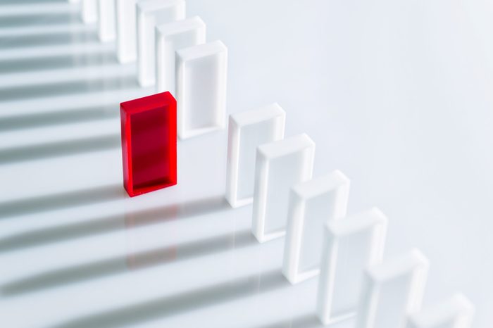 The red domino stands out among a line of white dominoes. no pips.