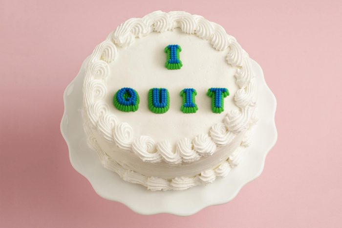 white cake on pink background with "i quit" on the cake