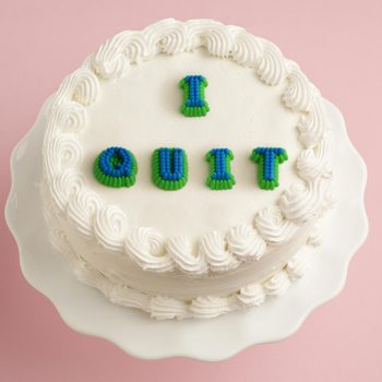 white cake on pink background with "i quit" on the cake