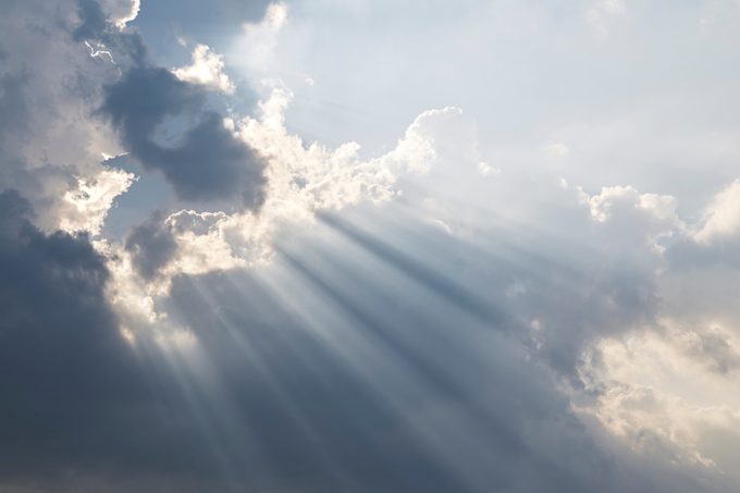 Dramatic Sky and Sun Rays Background. Sunbeams Light and Moody Cloudscape. Toned and Filtered Photo with Copy Space