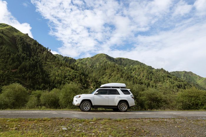 car on a road trip in the summer with mountains in the background