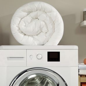 down comforter on top of a washing machine in laundry room