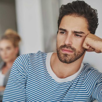 Close up of dissatisfied man with woman with crossed arms in background