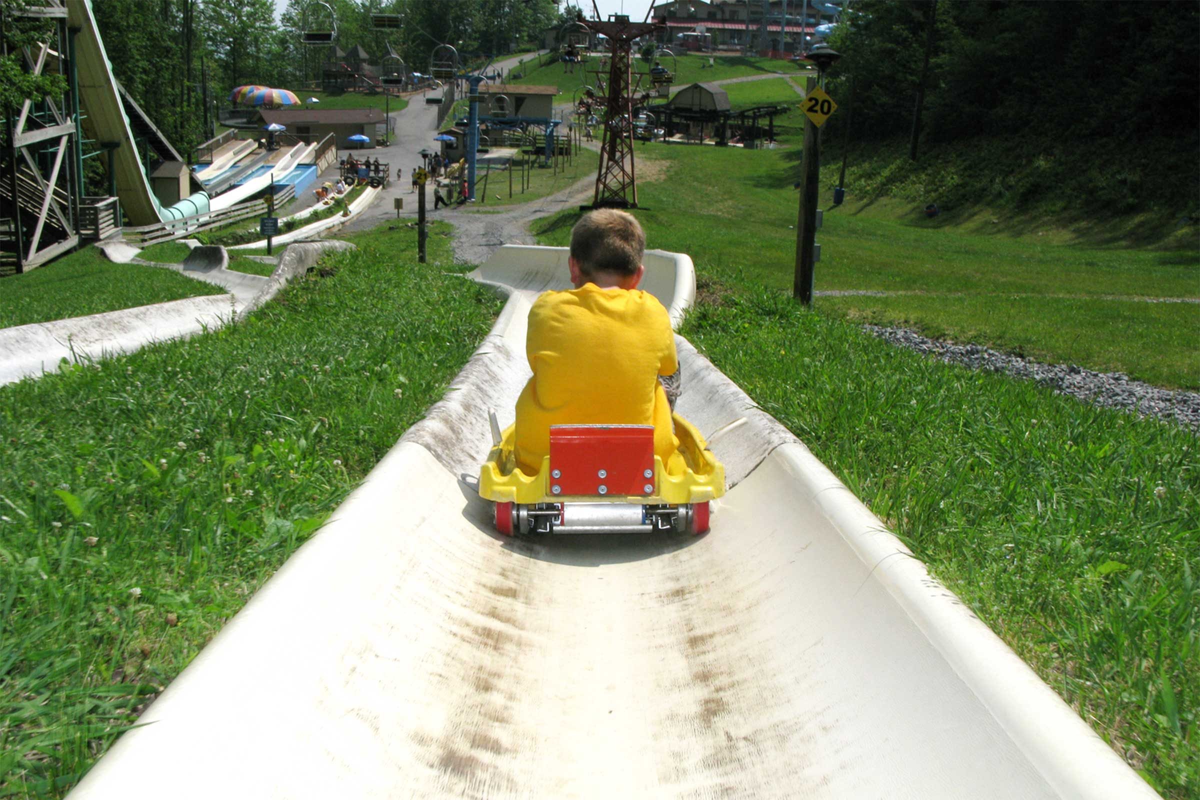 young boy sliding down Attitash Mountain