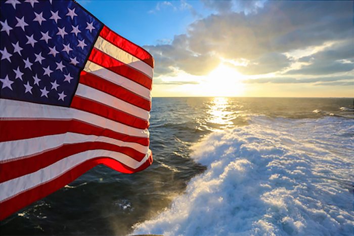 view of the sun, an american flag, and the Atlantic Ocean from the top of the sail of the USS Norfolk