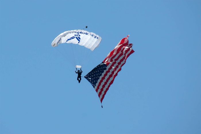 a member of the U.S. Air Force Academy Wings of Blue precision parachute team floats through the clear blue skies above Davis-Monthan Air Force Base in Tuscan, Arizona with an american flag