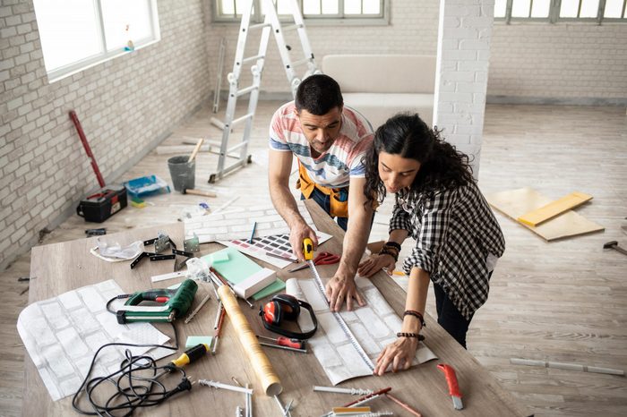 Couple making home improvement, measuring, high angle view.