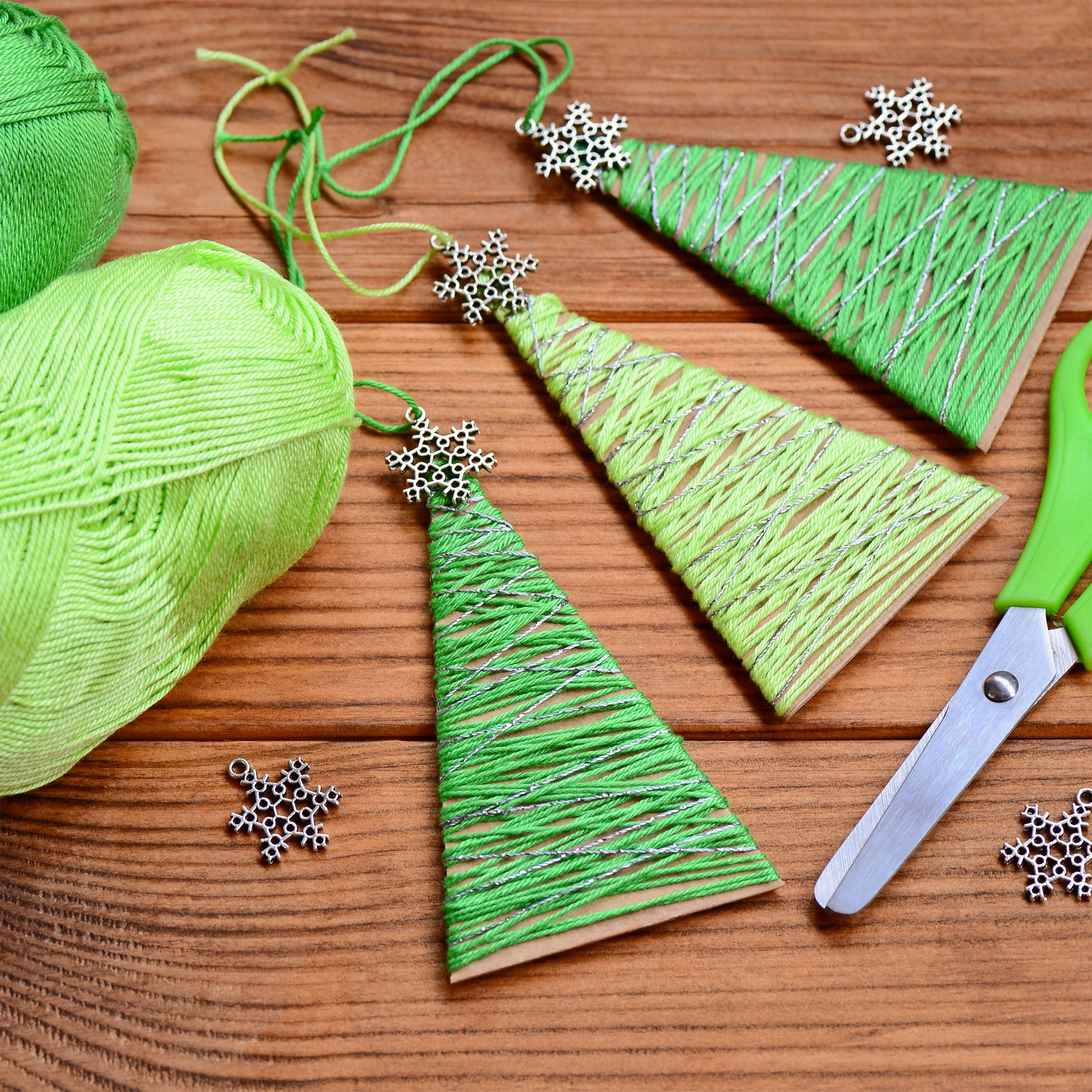 Little Christmas trees are made of carton, cotton yarn and decorated with small metal snowflakes