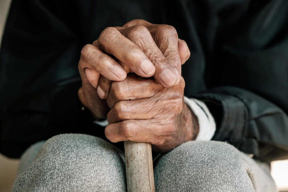 hand of a old man begging for money because of the hunger holding a cane.vintage tone