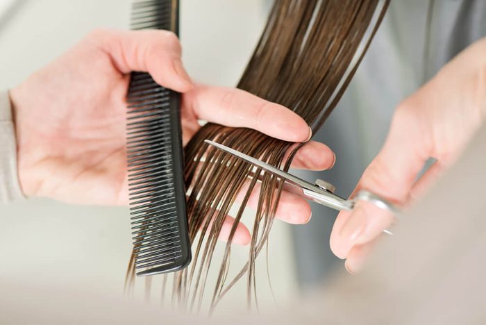 Hairdresser cut hair of a woman. Close-up.