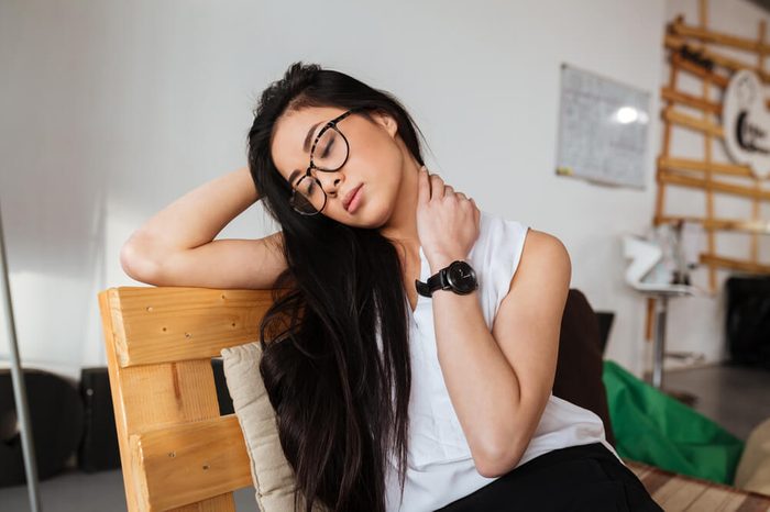 Tired exhausted asian young woman in glasses sitting and relaxing