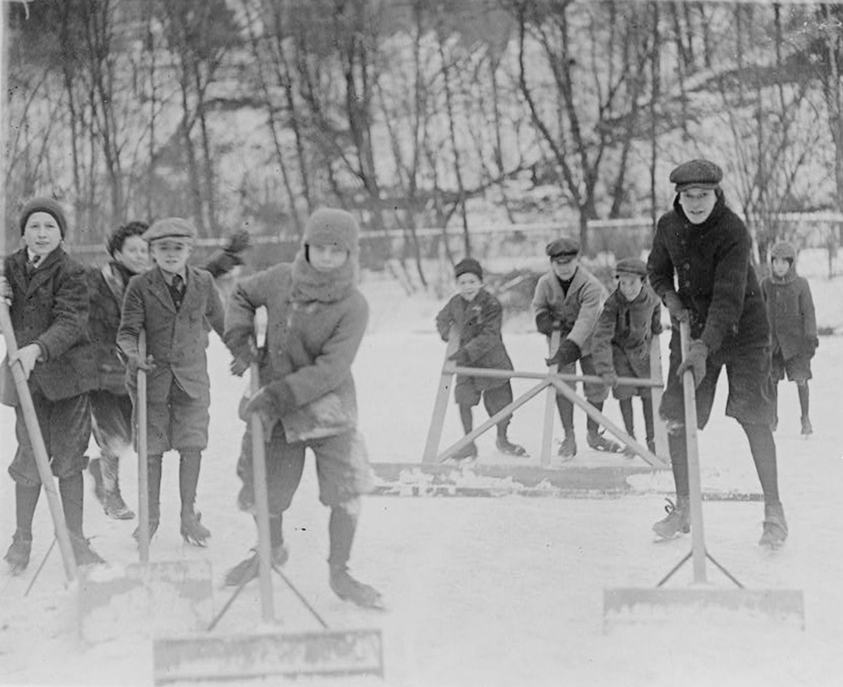 Boys cleaning snow off ice