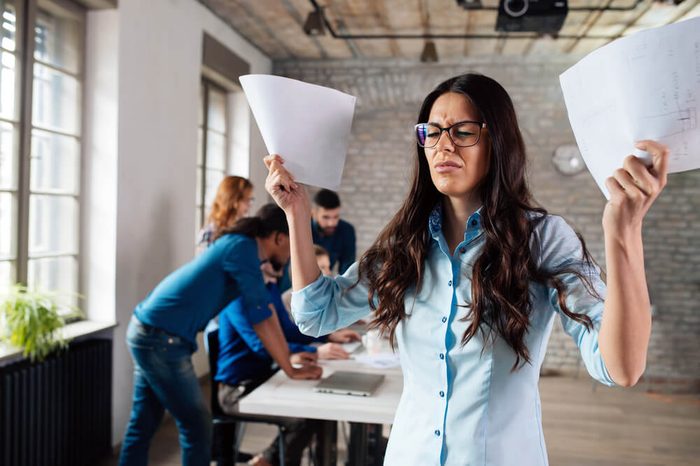 Overworked stressful businesswoman overwhelmed with papers in office