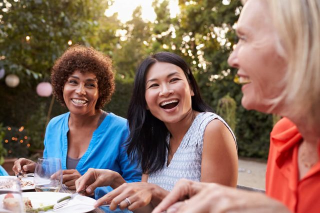 Mature Female Friends Enjoying Outdoor Meal In Backyard