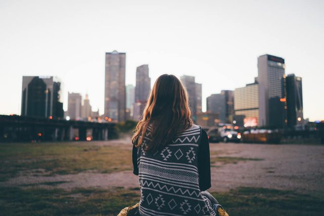 A traveler brunette girl is looking at the city skyline during in the evening.