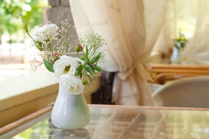 Closeup of rose flower bouquet in a vase on a sunny summer day in cafe. Main focus on flowers