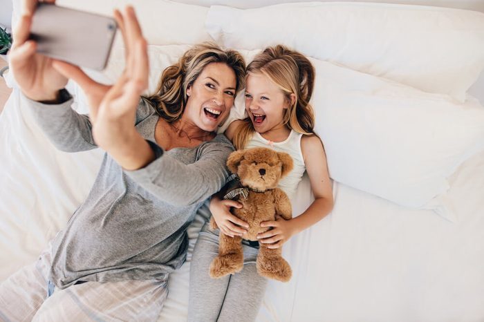 Happy young mother taking selfie with her daughter. Young family taking selfie on bed at home.