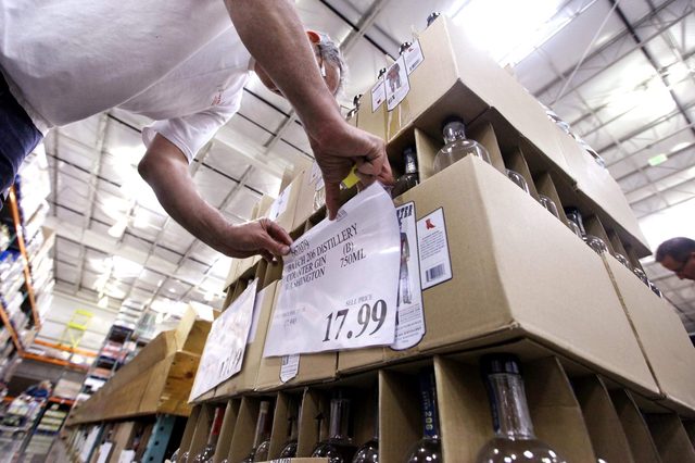 Store wine steward Robert Shelden places price signs on boxes of gin at a Costco warehouse store, in Seattle. Private retailers begin selling spirits for the first time under a voter-approved initiative kicking the state out of the liquor business. The initiative allows stores larger than 10,000 square feet and some smaller stores to sell hard alcohol