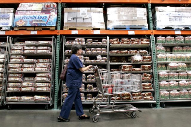 A shopper walks past shelves of bread at a Seattle Costco store . Costco Wholesale Corp. reported a 32 percent jump in its fiscal third-quarter profit Thursday, topping Wall Street expectations, as cash-squeezed customers flocked to its warehouse clubs in search of bargains on food and toiletries