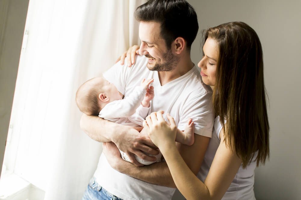 Happy family with newborn baby by the window