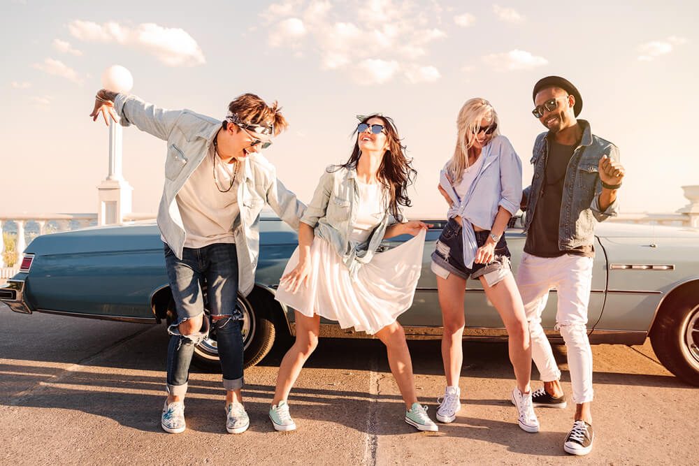 Group of cheerful young friends dancing together outdoors