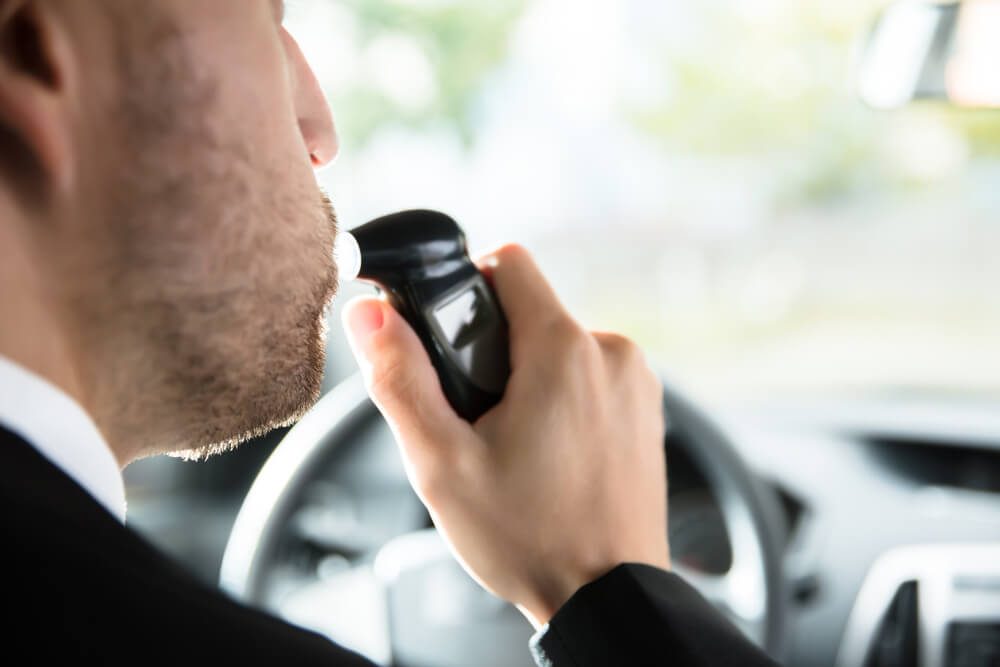 Close-up Of A Man Sitting Inside Car Taking Alcohol Test