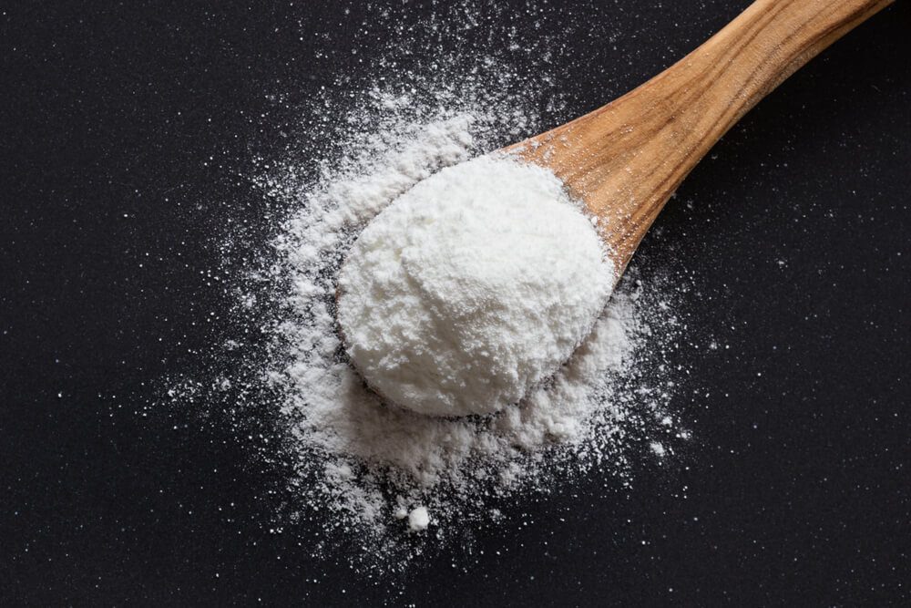 Baking soda on a wooden spoon on dark background, top view, sodium bicarbonate, powder, natural, cooking, baking, 