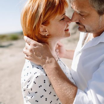 couple middle-age years in white shirts walks between sandstone rocks. holding hands, hugging, kissing. happiness love. standing against the sky. close-up portraits gentle