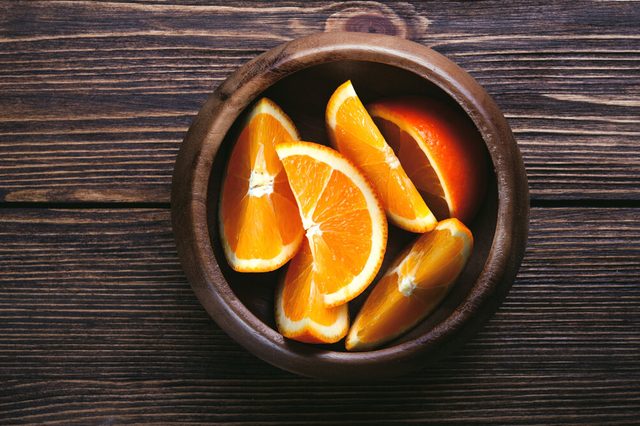 Slices of orange wooden bowl on wooden table. Top view. Toned