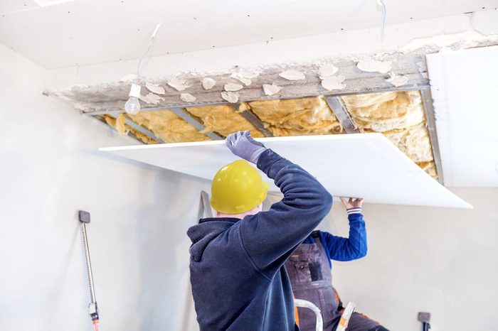 Workers assemble a suspended ceiling with drywall