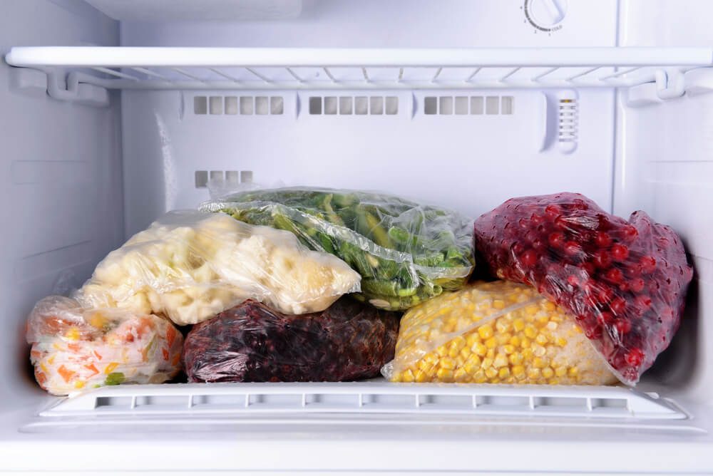 Frozen berries and vegetables in bags in freezer close up