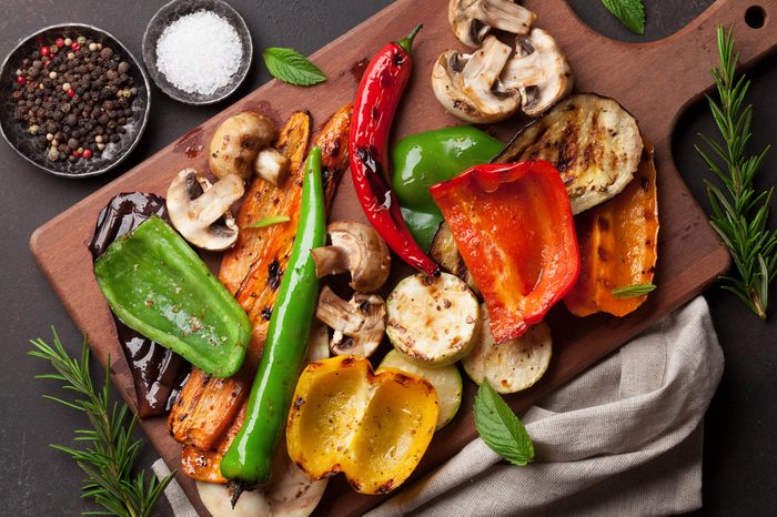 Grilled vegetables on cutting board on dark stone table. Top view