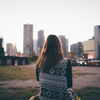 A traveler brunette girl is looking at the city skyline during in the evening.