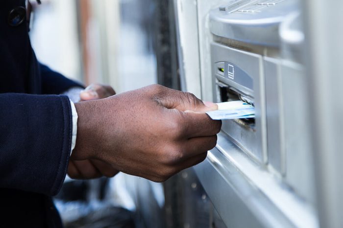 Close up of man taking cash from ATM with credit card.