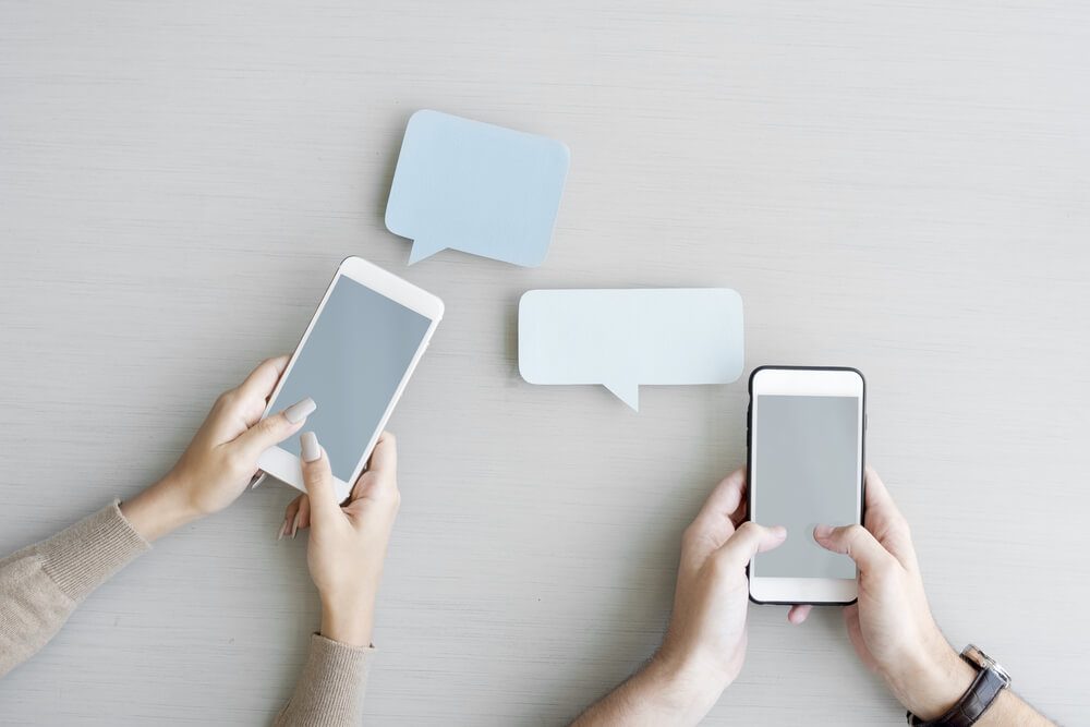 Hands Holding Mobile Phone with Blank Speech Bubble