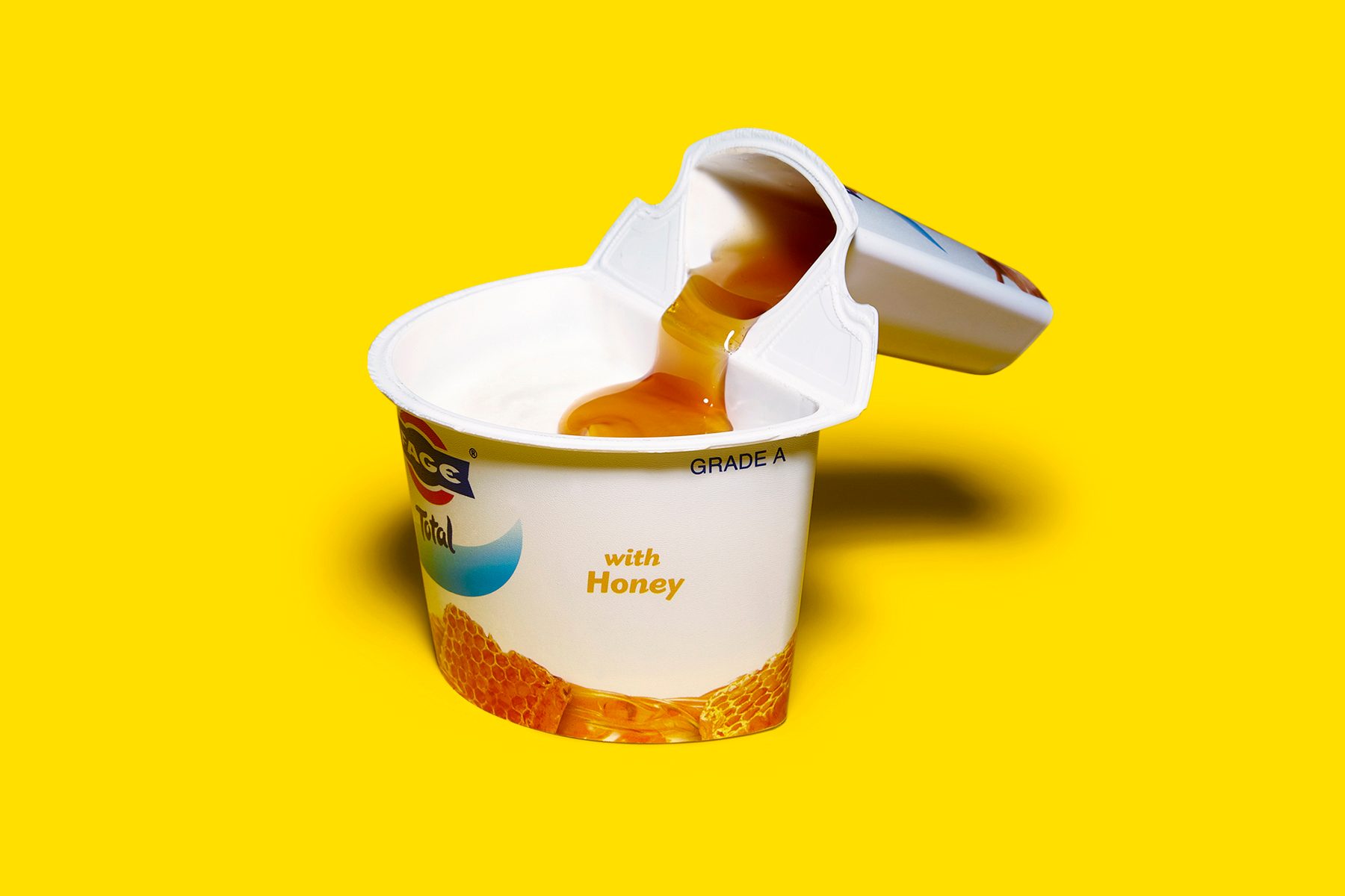 yogurt container with topping compartment folded to pour topping into yogurt