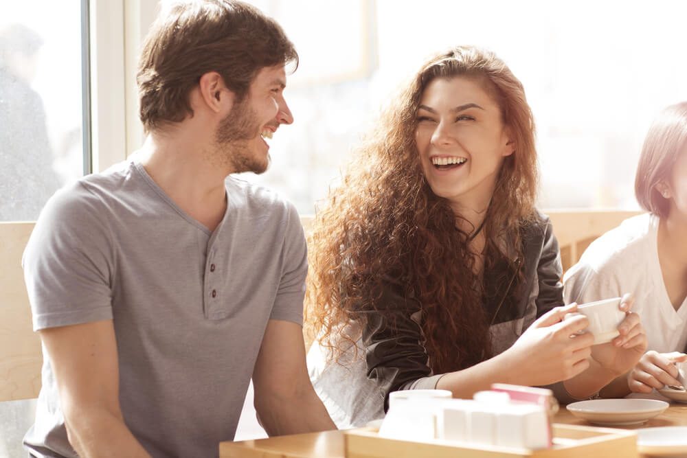 Shot of two young cheerful friends talking in a cafe laughing joyfully. Beautiful young woman laughing excitedly with her male friend people relationships couple date friendship leisure lifestyle