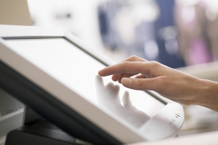 Closeup of woman's hand touching screen of cash register in store