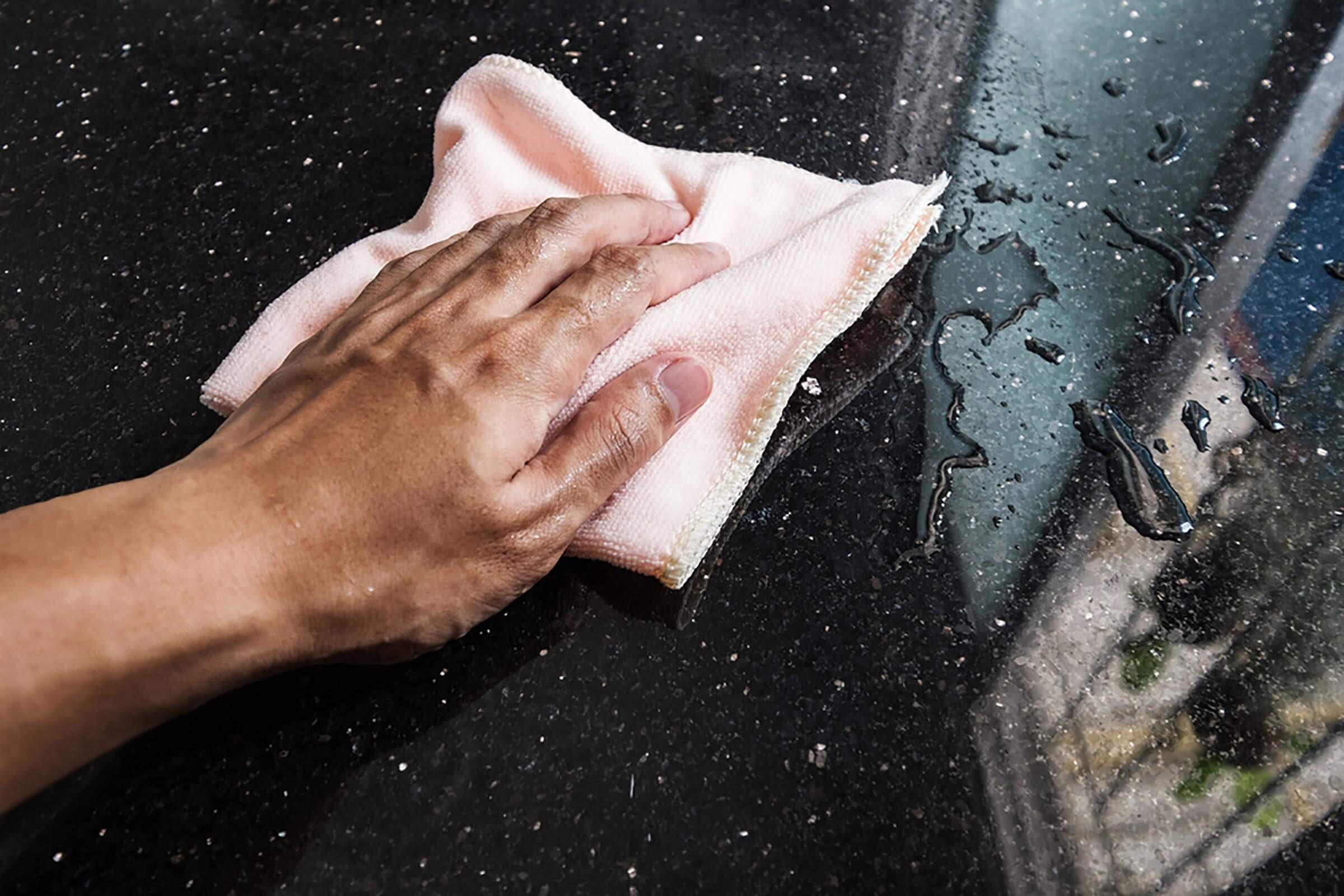 Hand cleaning black marble stone counter bar