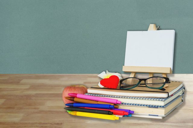 School, education, teacher's day and literacy concept with student and teacher stationery and supples on wood table over grey wall background
