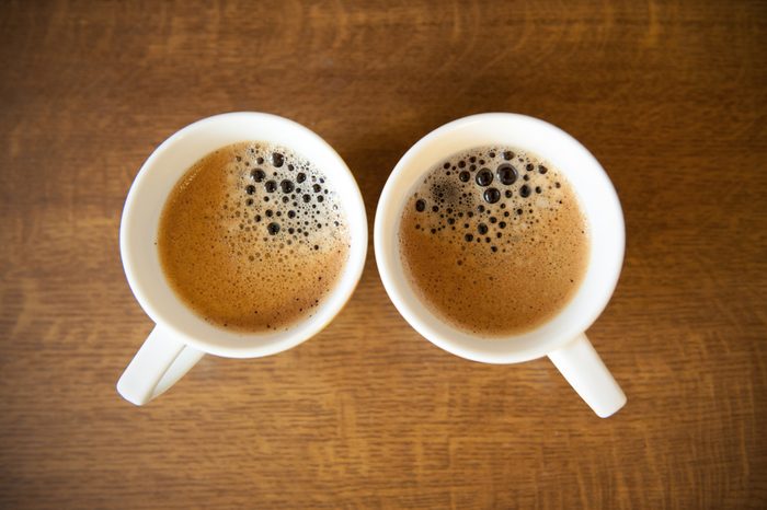 Two white cups with espresso on wood table