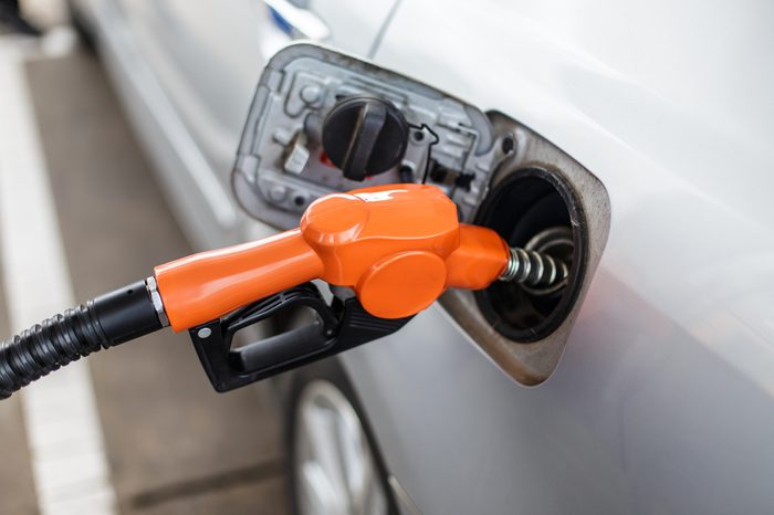 Gas pump nozzle in the fuel tank of a bronze car.