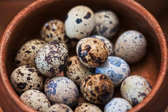 Fresh chicken eggs and quail eggs at wooden plate closeup