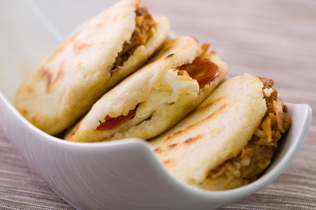 Close up of a traditional delicious arepas, shredded chicken avocado and cheddar cheese and shredded beef on wooden background