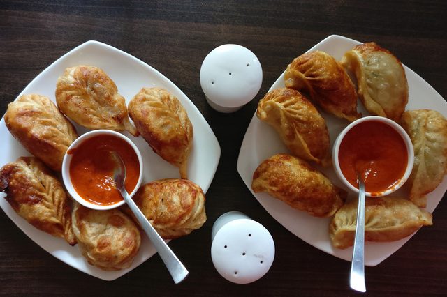 Veg fried cheese momos with sauce in white plates on a wooden table.