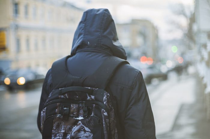 Student with backpack walking through foggy city street