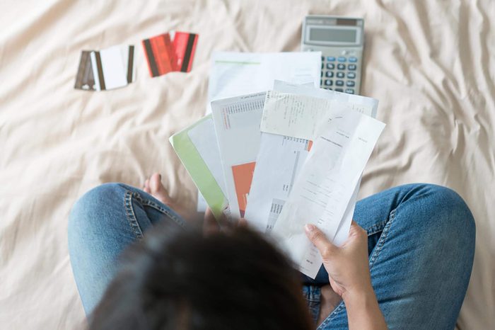 Top view of stressed young asian woman trying to find money to pay credit card debt.