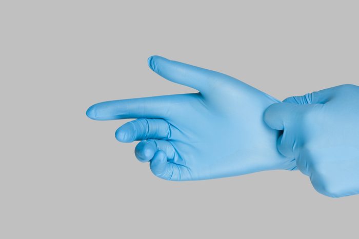 Blue gloves on a hand on a grey background